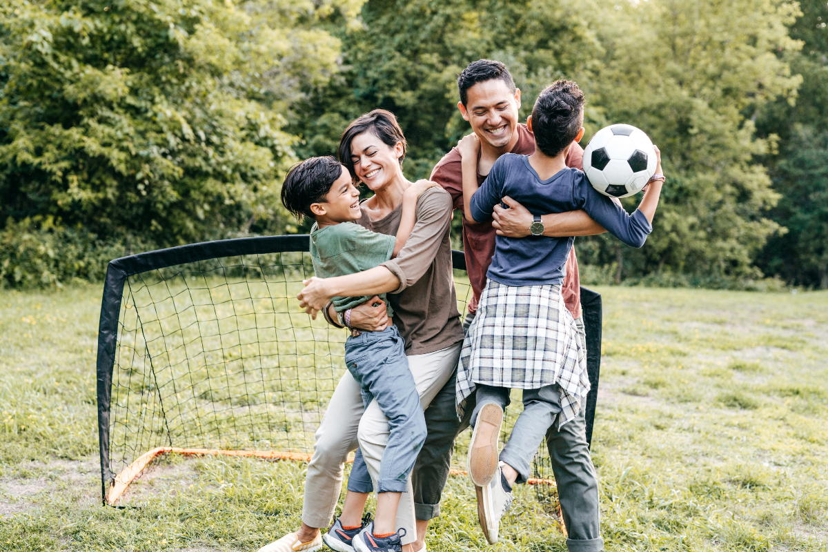 Warum ist Bewegung wichtig: Eltern und Kinder spielen Fußball