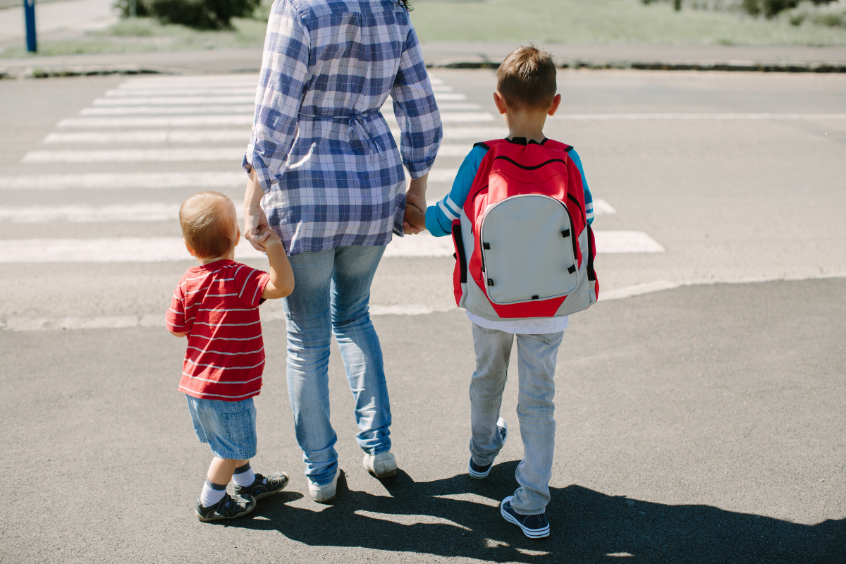 Sicherer Schulweg: Mutter mit Kindern gemeinsam auf dem Weg in die Schule