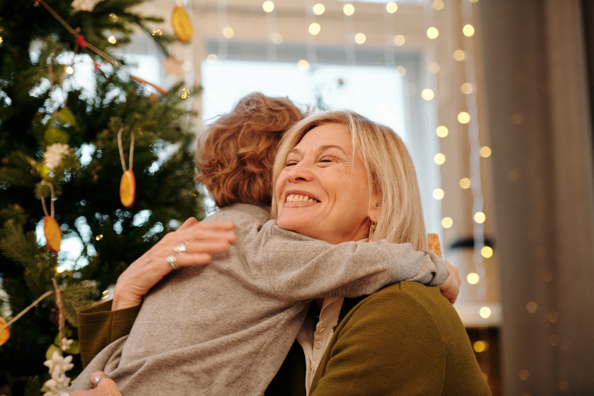 Last Minute Weihnachtsgeschenke für Kinder_Mutter umarmt Sohn vor Weihnachtsbaum