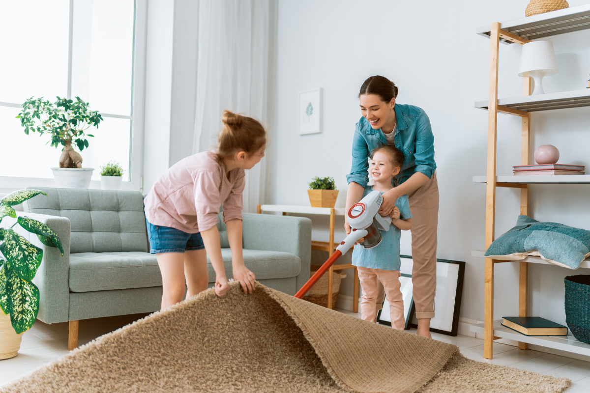 Neujahrsputz mit der Familie_Mutter und Töchter saugen Teppich