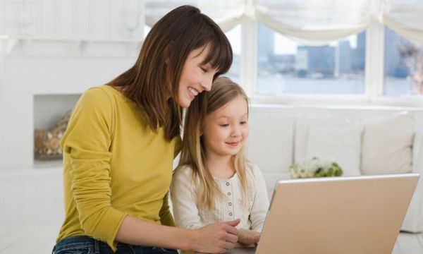 Homeoffice und Homeschooling: Mutter mit Tochter zuhause beim Lernen am Laptop