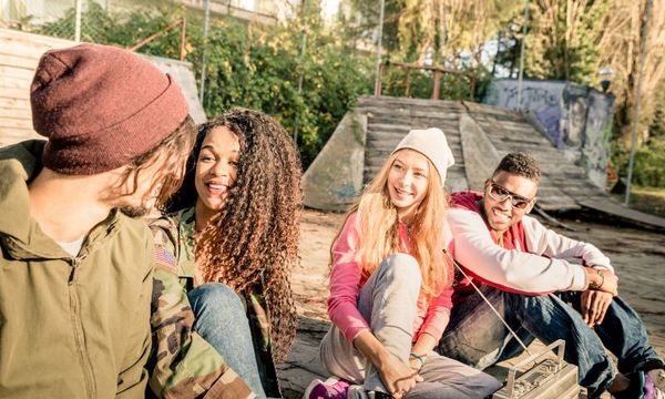 Pubertät und Schule: Jugentliche sitzen zusammen draußen