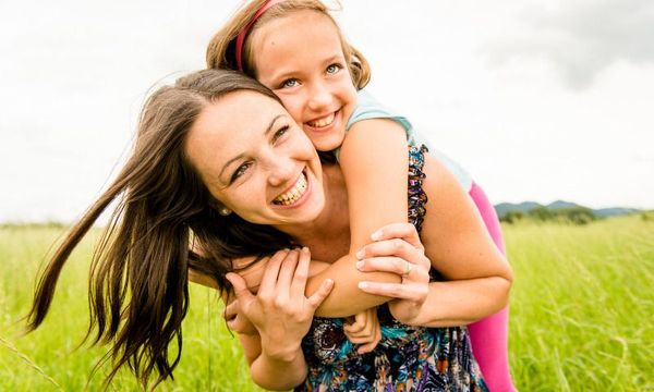 Selbstbewusstsein bei Kindern staerken: Mutter mit Tochter glücklich im Freien