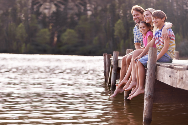 Urlaub am See: Familie sitzt fröhlich am See