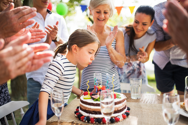 Einschlungsfeier: Kind pustet Kerzen auf Torte aus