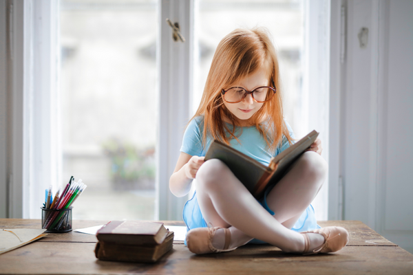 Kinder zum Lesen motivieren_Mädchen liest auf Fensterbank