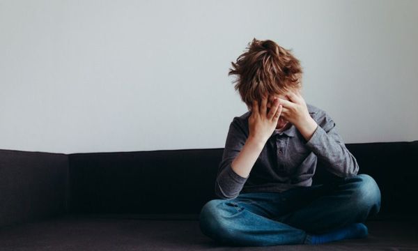 Schulstress: Junge sitzt ueberfordert und allein auf der Couch