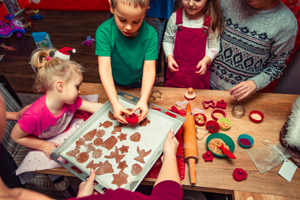 Backen mit Kinder: Kinder legen Plaetzchen aufs Backblech